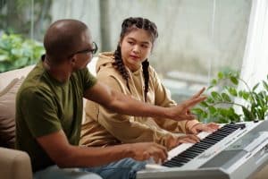 Music teacher explaining teenage girl who to play synthesizer