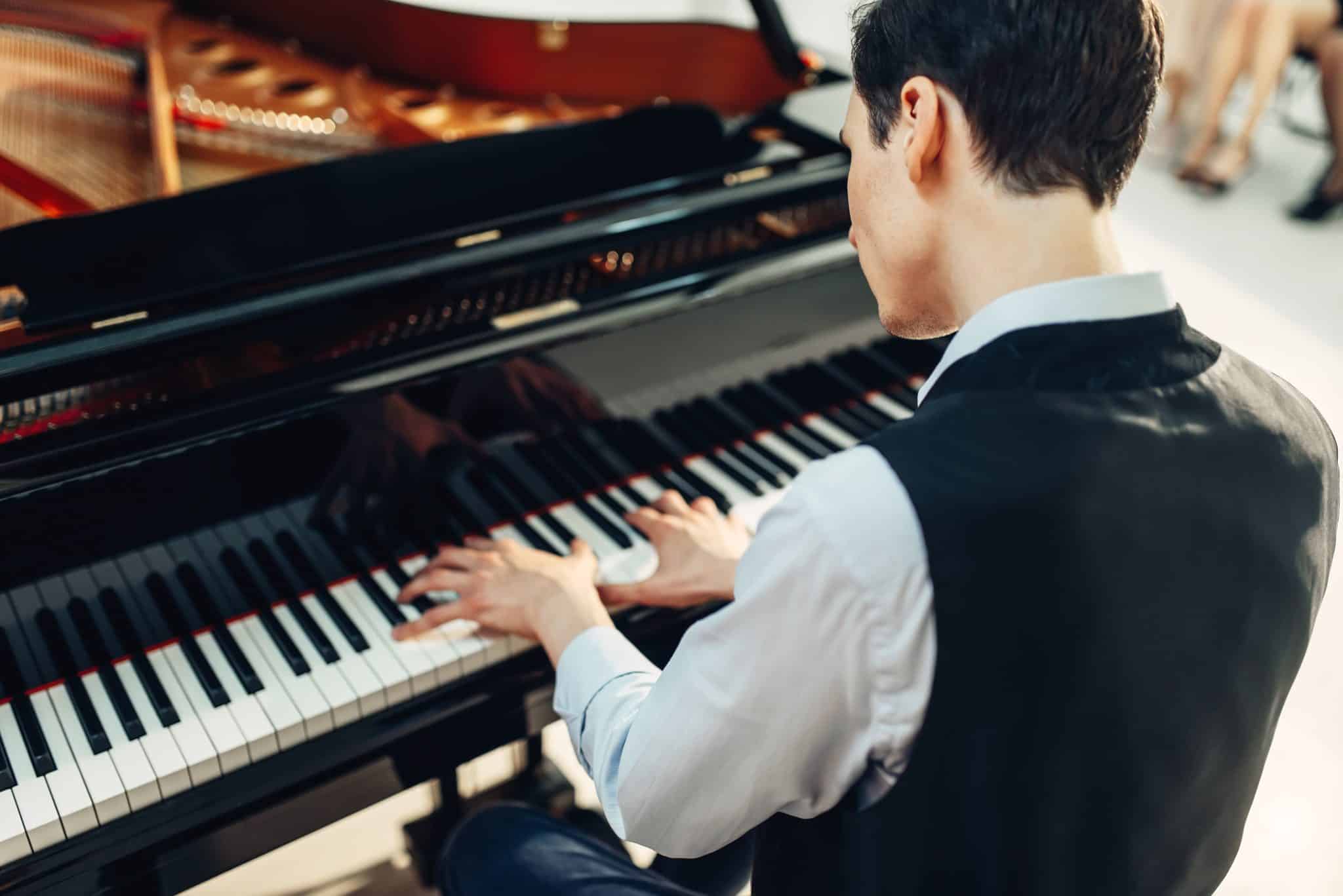 Pianist playing music on grand piano, back view. Musician practicing melody at the royale, classical musical instrument