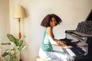 Young black lady playing a piano. Happy smiling woman enjoy fun learning to play piano music instrument.