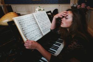 Woman reading sheet music at the piano, looking frustrated